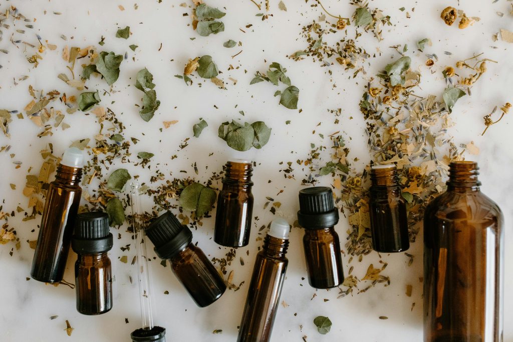 Flat lay of brown glass bottles and dried herbs, perfect for aromatherapy themes.